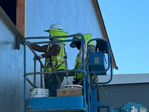 Crew on a lift applying an air and vapor barrier to an exterior wall